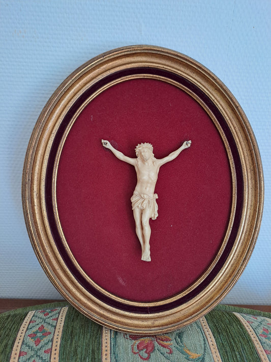 Cadre ovale. Jesus crucifié sur daie de velours rouge.